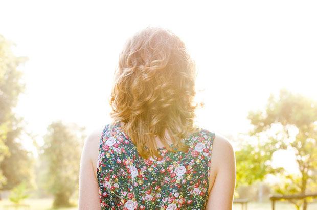 Back of girl's head as she stands in a garden in sunshine