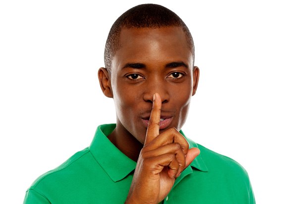Young man holding his index finger to his lips