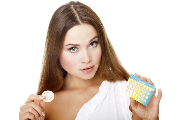 Girl holding a condom and pills
