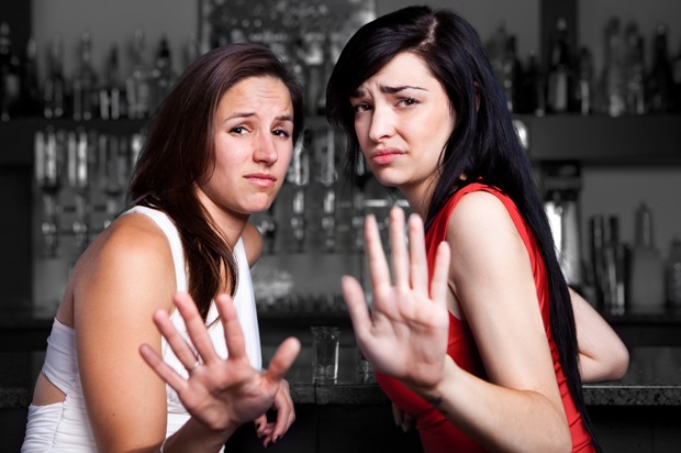 Two upset looking girls holding their hands up to someone.