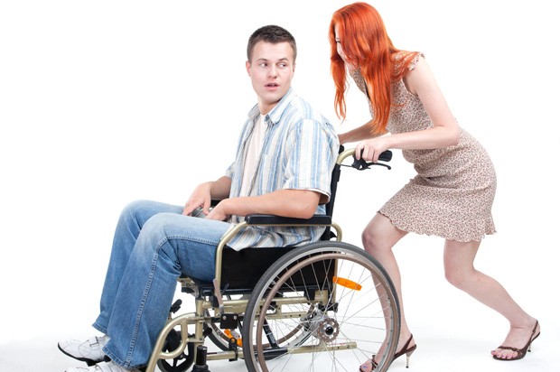Young woman pushing a young man in a wheelchair