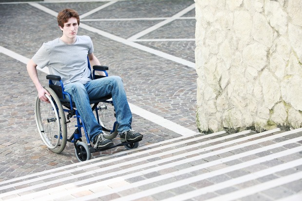 A young man in a wheelchair unable to get up the stairs
