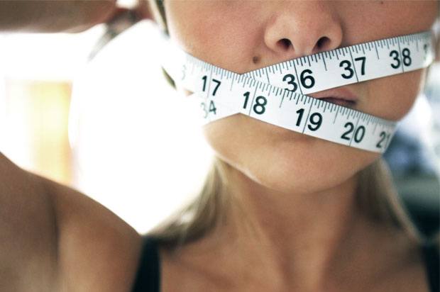 Girl holding a tape measure around her mouth