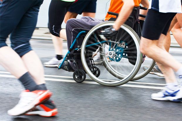 One person in a wheelchair surrounded by people running