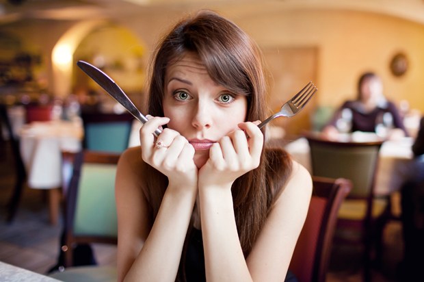 Girl holding a knife and fork looking fed up