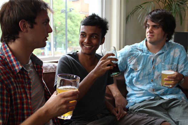 Three boys on a sofa chatting and having a drink