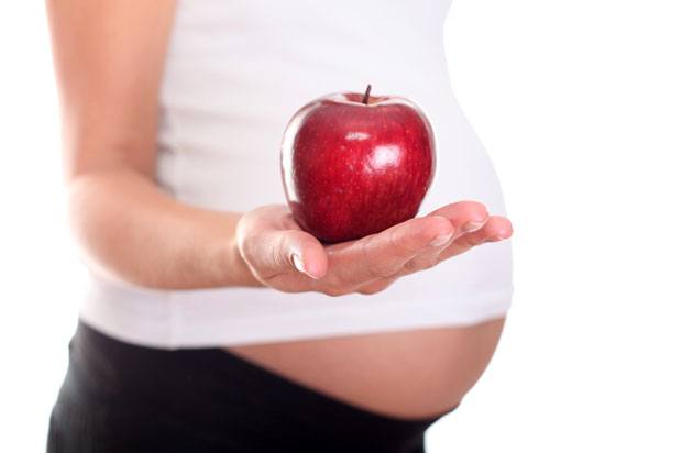 pregnant woman holding an apple.