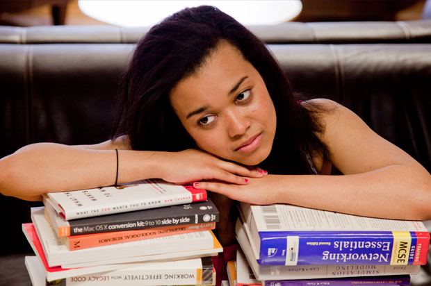 Girl looking tired on a pile of books