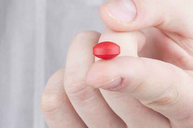 Red pill being held on a finger