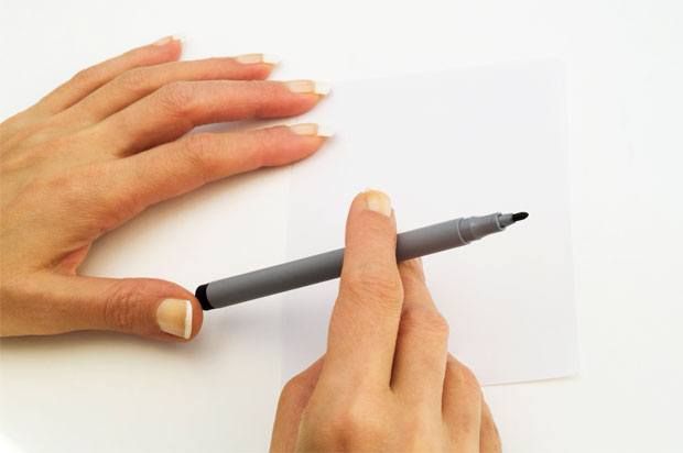 hands holding a pen with carefully manicured nails.