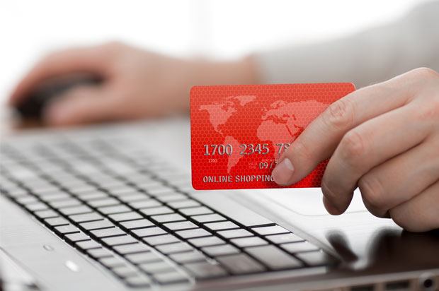 Hand holding credit card in front of computer keyboard