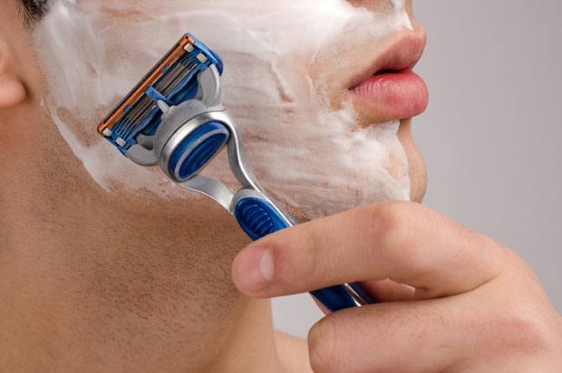 Man with shaving foam on his face beginning to shave with a razor