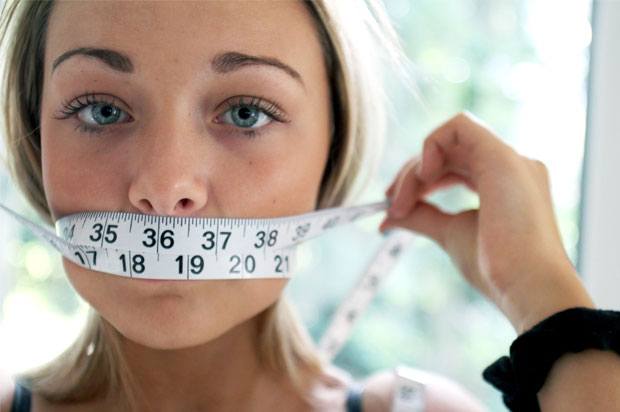 Girl with tape measure over her mouth