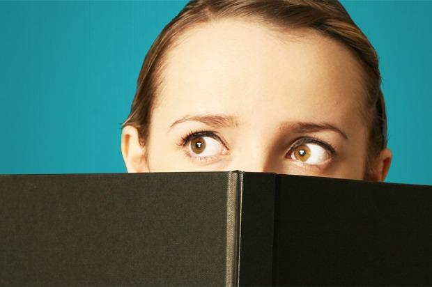 Girl peeping over a book