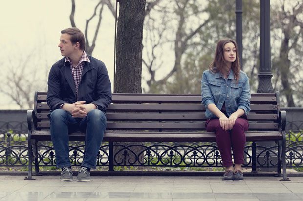 boy and girl sitting apart on bench