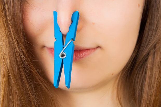 Girl with a blue clothes peg on her nose.