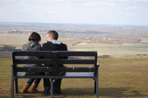 girl and boy sat on a bench in the countryside