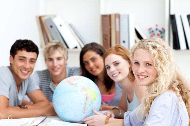 Students smiling all sat around a globe