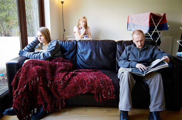 Girl sat on other side of sofa from dad and mum sat behind