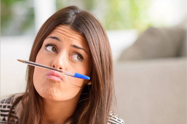 Girl looking confused with a pen resting under her nose