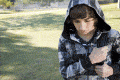 boy with hood up looking down carrying rucksack